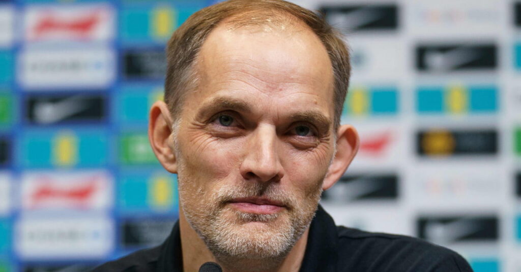 Le manager du football Thomas Tuchel regarde vers le haut lors d'une conférence de presse et sourit tout en portant un haut sombre