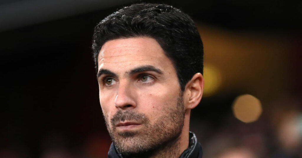 Le manager de football Mikel Arteta regarde à sa droite avec un air concentré dans une zone technique d'un stade dans son rôle d'entraîneur-chef d'Arsenal tout en portant un polo noir