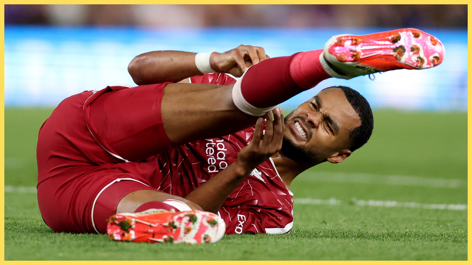 L'ailier de Liverpool Cody Gakpo est allongé sur le sol, se tenant la jambe douloureuse.
