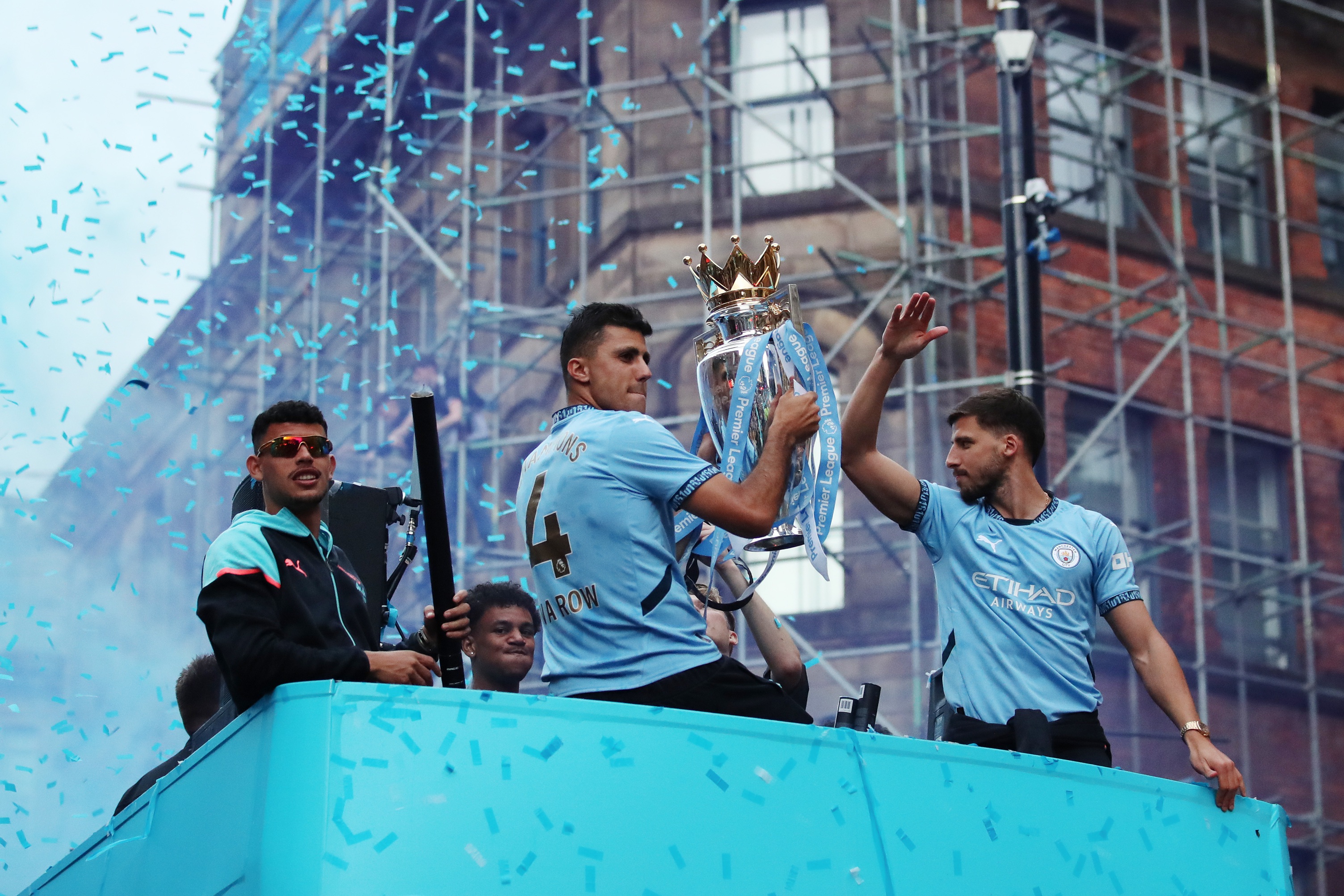 Rodri détient le trophée de la Premier League lors d'une célébration du bus à toit ouvert avec ses coéquipiers de Man City.