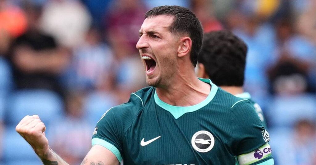 Le footballeur Lewis Dunk lève et serre le poing droit et rugit pour célébrer un but alors qu'il joue pour l'équipe de Premier League Brighton and Hove Albion Football Club dans une chemise verte avec l'insigne du club et le logo Nike sur la chemise