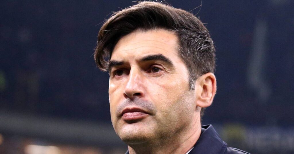 Paulo Fonseca, entraîneur de football, portant un imperméable foncé et une chemise blanche et regardant à sa droite dans un stade en tant qu'entraîneur-chef de l'Olympique Lyonnais ou du club de Ligue 1 Lyon